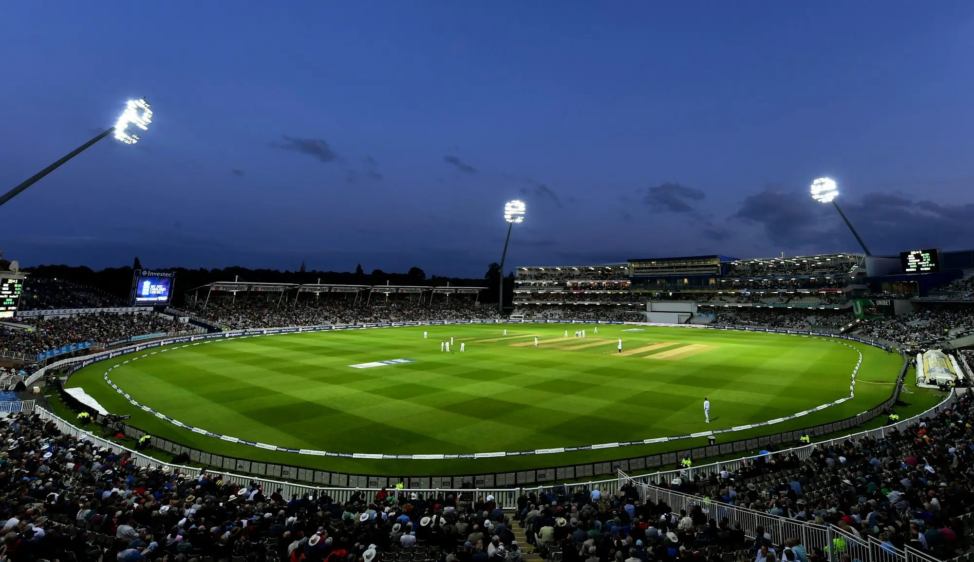 Floodlit cricket stadium at dusk